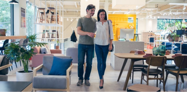 Una pareja en una tienda de muebles disfrutando los beneficios de su tarjeta.