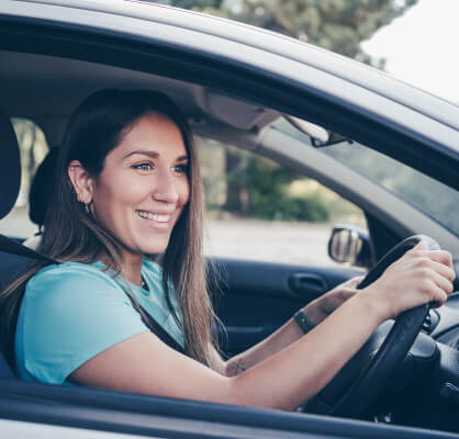 Una mujer manejando su auto.